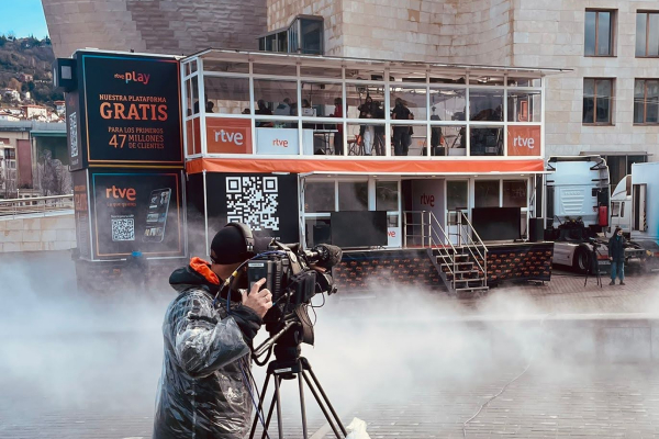 Imagen de un evento, en primer término un cámara con una nuve de humo